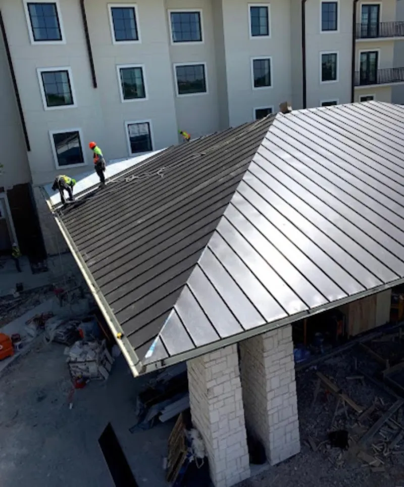 Crew installing standing seam metal roof panels on a commercial project in Riverdale